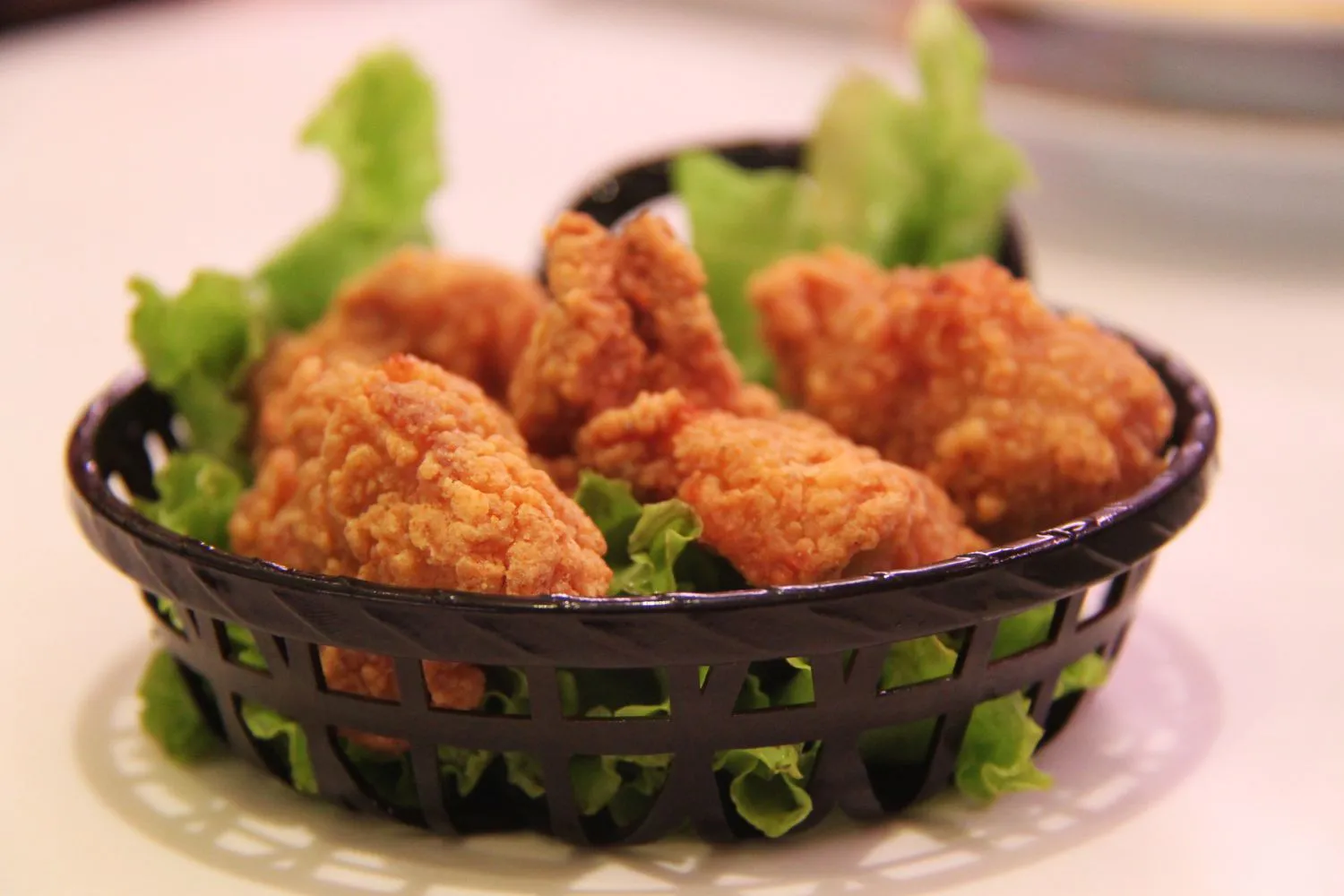 Breaded fried chicken bites in a black basket at MBL & Q Burger, a Fried Chicken Shop in Irvine